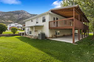 Rear view of property with a lawn, central AC, a mountain view, and a patio area