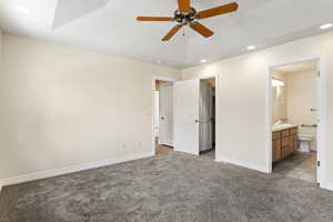 Unfurnished bedroom featuring light carpet, ceiling fan, ensuite bathroom, and sink