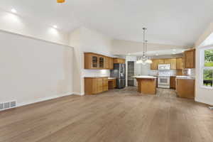 Kitchen featuring pendant lighting, white appliances, a center island, a notable chandelier, and light hardwood / wood-style floors