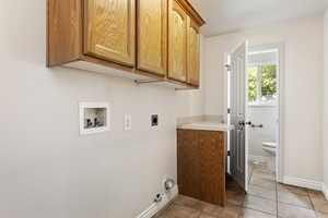 Laundry area with washer hookup, light tile patterned floors, gas dryer hookup, cabinets, and electric dryer hookup