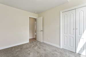 Unfurnished bedroom with light carpet and a closet