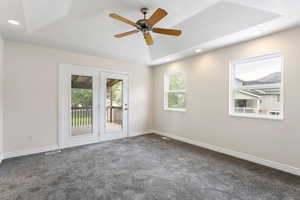 Spare room featuring dark carpet, ceiling fan, a raised ceiling, and a textured ceiling