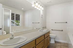 Full bathroom featuring vanity, separate shower and tub, toilet, and tile patterned floors