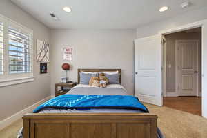 Guest Bedroom #3 w/ light carpet flooring, recessed lighting & large windows w/ plantation shutters.