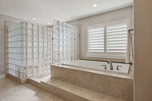 Primary Bathroom w/ separate sunken tub & luxe glass block enclosed walk-in shower.