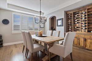 Formal Dining area w/ hardwood flooring, custom circular metal light fixture, recessed lighting & custom distressed wood wine credenza.