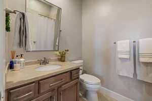 Main floor guest bedroom full ensuite bathroom w/ granite counter vanity & custom pivoting metal framed mirror.