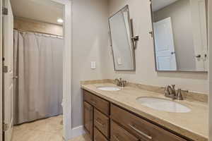 Full "Jack & Jill" bathroom between Guest Bath #2 & #3 featuring tile flooring, dual vanity sinks & custom pivoting metal framed mirrors.