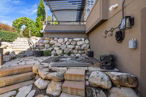 View of natural stone exterior nook w/ stone stairway, patio & sunken hot tub.