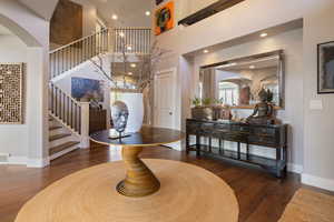 Double volume entryway foyer w/ hardwood flooring, grand stairway & art niche wall w/ recessed ambient lighting.