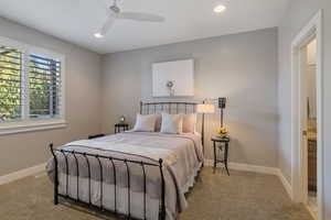 Main floor guest bedroom w/ light carpet flooring, ceiling fan, recessed lighting & full ensuite bathroom.