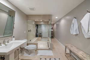 Bathroom with toilet, sink, tile patterned floors, and an enclosed shower