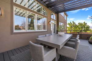 Outdoor dining area on rear deck, shaded by a large wooden trellis above.