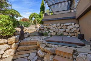 Natural stone stairway leading to backyard & stone patio featuring a sunken hot tub.