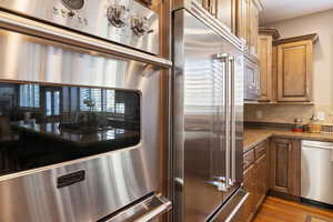 Kitchen featuring built in Viking s.s. appliances, granite counters, decorative backsplash & hardwood flooring.