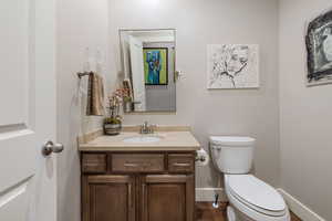 Main floor 1/2 bath w/ hardwood flooring, granite counter & custom pivoting metal framed mirror.