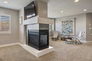 Multi-sided gas fireplace separating Primary Bedroom & sitting/lounge nook w/ recessed lighting, large windows & plantation shutters.