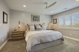 Spacious Primary Bedroom w/ large windows, planation shutters, recessed lighting & light carpet flooring.