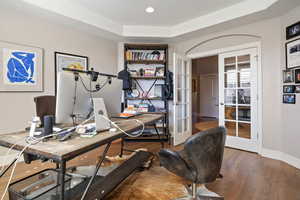 Home office w/ glass paneled French doors, hardwood flooring, recessed ceiling w/ recessed can lighting.