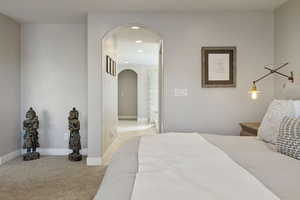 Open archway leading into tile floored Primary Bathroom off of Primary Bedroom.