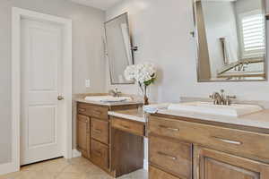 Primary Bathroom w/ dual vanity sinks, custom pivoting metal framed mirrors & tile flooring.