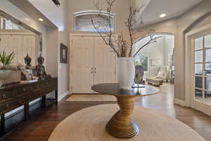 View of entryway foyer featuring a towering ceiling, hardwood flooring & art niche wall w/ recessed ambient lighting.