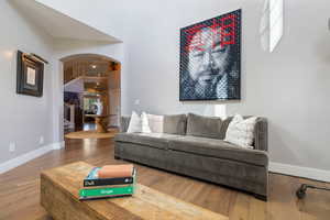 Living Room off of entryway foyer w/ open archway, hardwood flooring, recessed lighting & double height ceiling.