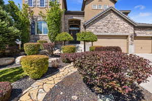 View of entryway w/ natural stone walkway & well-manicured landscaping.