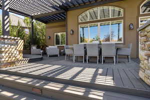 Rear wood deck w/ outdoor dining area shaded by wooden trellis above.