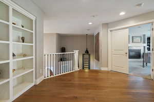 Upstairs loft area w/ hardwood flooring, built-in shelving nook & recessed lighting.