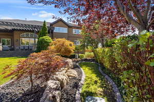 Backyard view of house & wooden trellis covered back deck & matured landscaping.