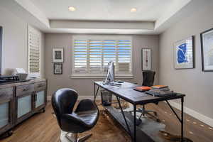 Home office space w/ recessed ceiling, hardwood flooring, large windows w/ plantation shutters & recessed lighting.