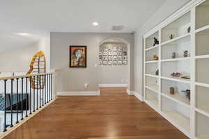 Upstairs loft space w/ hardwood flooring, built-in shelving nook & recessed lighting.