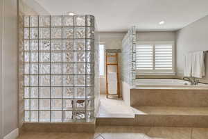 Primary Bathroom w/ separate sunken tub & luxe glass block enclosed walk-in shower.