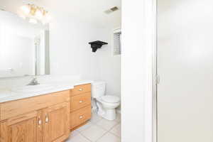 Bathroom with walk in shower, tile patterned flooring, vanity, and toilet