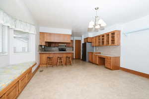 Kitchen with stainless steel fridge, tasteful backsplash, decorative light fixtures, sink, and a notable chandelier