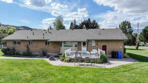 Back of house with central AC unit, a lawn, and a patio area