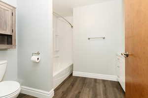 Bathroom featuring wood-type flooring, bathing tub / shower combination, and toilet