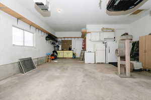 Garage featuring fridge, a garage door opener, and white fridge