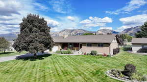 Ranch-style home featuring a mountain view, a garage, and a front lawn