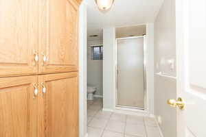 Bathroom with a textured ceiling, toilet, tile patterned floors, and an enclosed shower