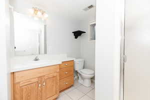 Bathroom featuring vanity, a shower with shower door, toilet, and tile patterned floors