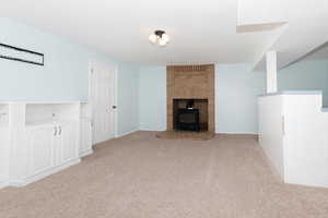 Unfurnished living room featuring light carpet and a wood stove