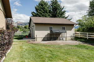 Back of house with a yard, a mountain view, and a patio area