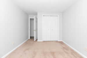 Unfurnished bedroom featuring light carpet and a closet