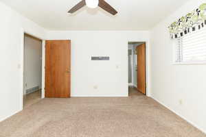 Carpeted master bedroom with ceiling fan and bathroom