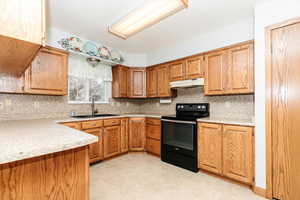 Kitchen with decorative backsplash, black electric range oven, and sink