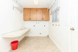 Washroom with washer hookup, light tile patterned floors, hookup for a gas dryer, cabinets, and electric dryer hookup