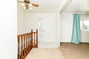 Carpeted entryway with ceiling fan