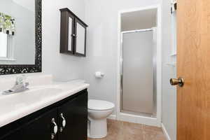 Bathroom featuring vanity, toilet, tile patterned floors, and a shower with shower door